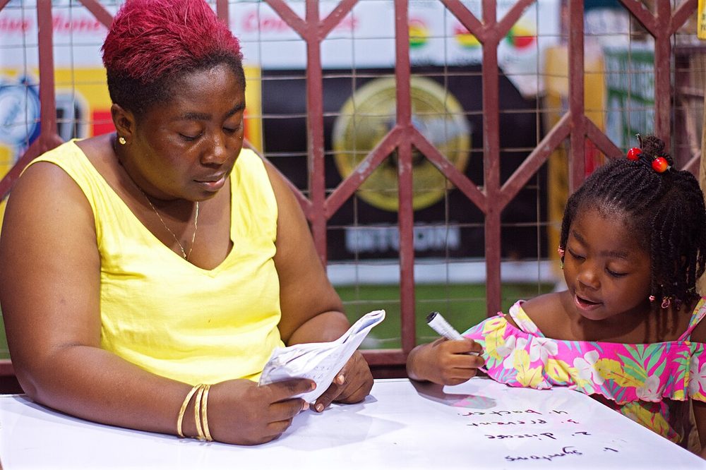 An adult helping a girl with homework at a table